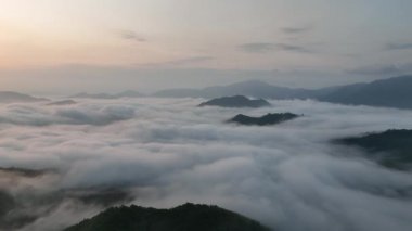 Slow aerial move in on mountain peaks in sea of clouds and morning fog. High quality 4k footage
