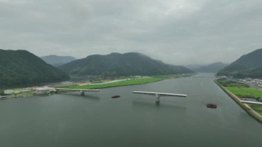 Slow move toward bridge under construction over river through mountains. High quality 4k footage