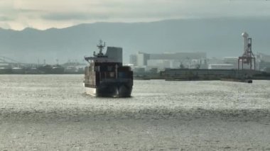 Fully loaded cargo ship slowly turns while entering industrial harbor. High quality 4k footage