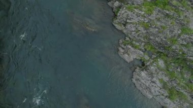 Water moves through rocky narrows in deep blue river. High quality 4k footage