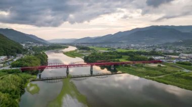 Hyperlapse: Light traffic over arched red bridge over river at dusk. High quality 4k footage