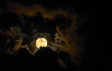Full moon glow illuminates clouds on dark night. High quality photo