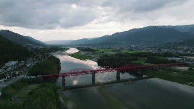 Red bridge across Yoshino River through valley and mountain landscape at dusk. High quality 4k footage
