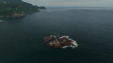 Rotating around small island shrine revealing coastal resort. High quality 4k footage