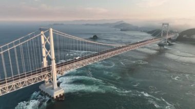 Strong current under suspension bridge across Naruto Straight at sunset. High quality 4k footage