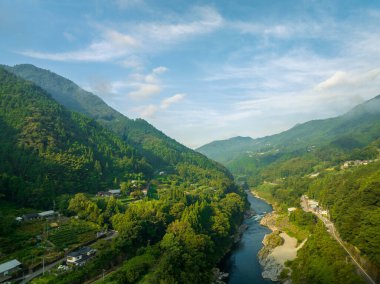 River flows through forested valley and small villages in morning sun. High quality photo
