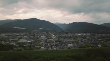 Aerial view of small town at foot of misty mountains in early evening. High quality 4k footage
