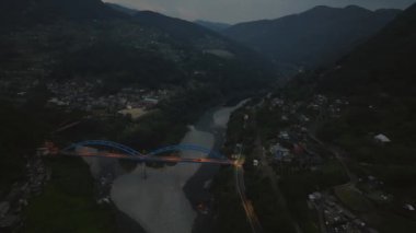 Aerial night view of blue bridge connecting small mountain villages. High quality 4k footage
