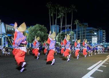 Tokushima, Japan - August 12, 2022: Women dance in unison wearing traditional kimonos and hats at Awaodori street festival. High quality photo