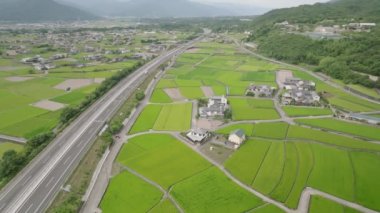 Aerial view of bus and light traffic on highway through rural rice fields. High quality 4k footage