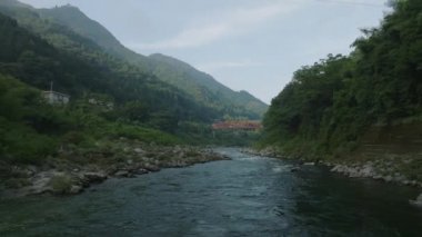 Flying low over rocky river at base of mountain. High quality 4k footage