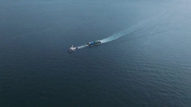 Aerial view of small boat towing floating cargo in calm blue sea. High quality 4k footage