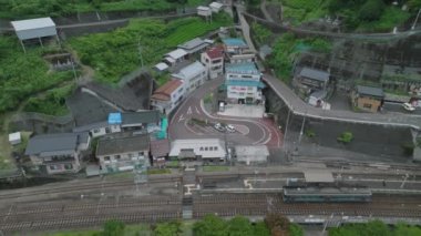 Aerial view of single car train at platform at station in small mountain village. High quality 4k footage
