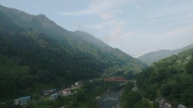 Early morning sun lights forested valley and houses along river. High quality 4k footage