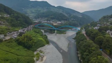 Hyperlapse: Cars zip by arched blue bridge connecting green mountains. High quality 4k footage