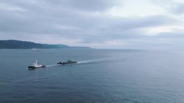 Small boat pulls cargo barge off coast at dusk. High quality 4k footage