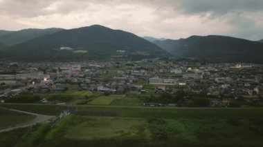 Aerial slide across small town at foot of mountains as night falls. High quality 4k footage