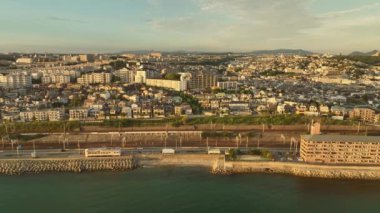 Slide past coastal town on gentle rolling hills in late afternoon sun. High quality 4k footage
