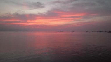 Flying low over calm coastal waters under pink sky at dawn. High quality 4k footage