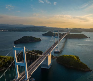 Overhead view of towers and roadway on long suspension bridge through small islands in late afternoon. High quality photo