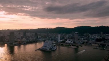 Pink sunset glow as small boats enter city harbor. High quality 4k footage