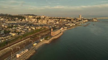 Flying along sprawling coastal town in late afternoon. High quality 4k footage