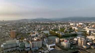 Slow move toward Japanese castle surrounded by moat and sprawling city in early morning light. High quality 4k footage