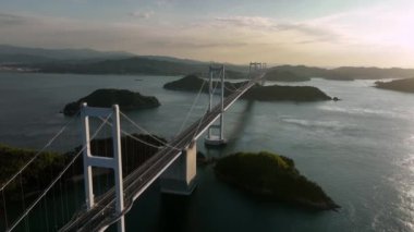 Aerial view of long suspension bridge between islands along Shimanami Kaido at sunset. High quality 4k footage