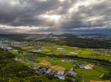 Japon kırsalındaki tarım arazilerinde tayfun bulutları arasından güneş parlar. Yüksek kalite fotoğraf