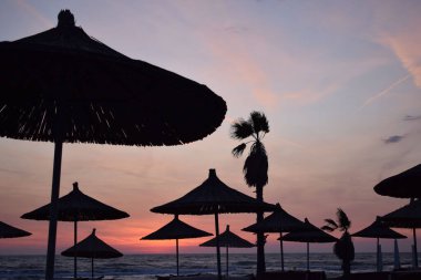 Sahilde gün batımında saman şemsiyesi silueti. Yüksek kalite fotoğraf