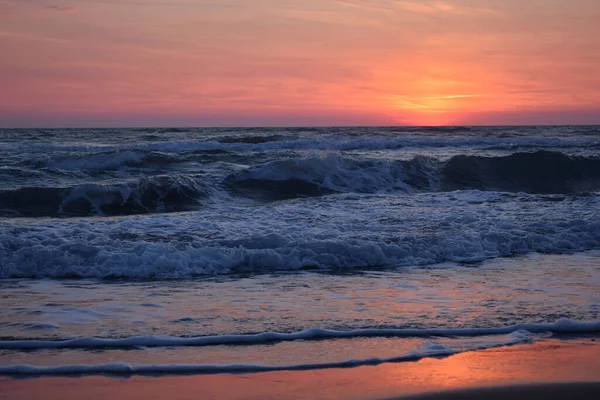 Ένα Όμορφο Ηλιοβασίλεμα Στην Παραλία Στον Ταραγμένο Ωκεανό Αποχρώσεις Πορτοκαλί — Φωτογραφία Αρχείου