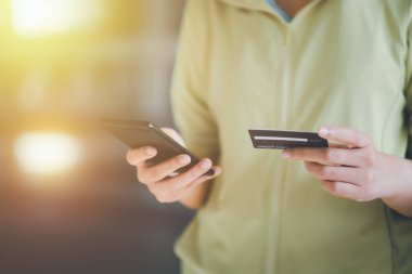 Kadınlar kredi kartı tutuyor ve cep telefonu kullanıyorlar. Çevrimiçi ödeme kavramı.