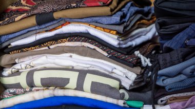 Dolapta bir sürü kıyafet var. Renkli katlanmış giysi yığını. Ev konsepti. Temiz çamaşır yığını.