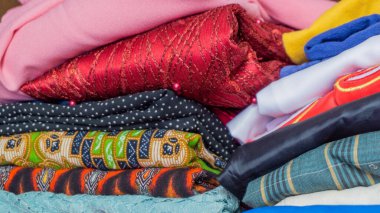 Dolapta bir sürü kıyafet var. Renkli katlanmış giysi yığını. Ev konsepti. Temiz çamaşır yığını.