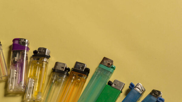 Top view of gas lighters with different colours on yellow background