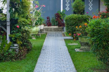 Binanın her bölümünü birbirine bağlamak için yürüyüş yolu ya da patika. Etrafında çiçekler ve bitkiler olan geçit ya da patika