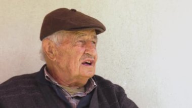 Kibar, yaşlı bir insan heyecanla arkadaşlarına bir şeyler anlatıyor.