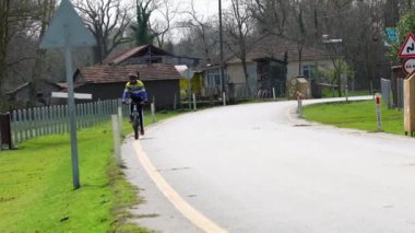 Spor giyimli güçlü bir adam ve siyah kasklı bir adam yolda bisiklet sürüyor. Olgun bir sporcu asfalt yolda en sevdiği hobisinin tadını çıkarıyor..