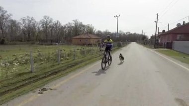 Spor giyimli güçlü bir adam ve siyah kasklı bir adam yolda bisiklet sürüyor. Olgun bir sporcu asfalt yolda en sevdiği hobisinin tadını çıkarıyor..