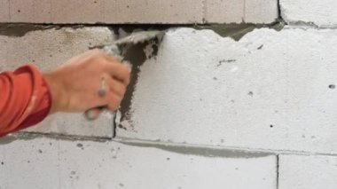 İnşaatçı bir spatulayla çalışıyor. Bir adam yapı taşları inşa ediyor