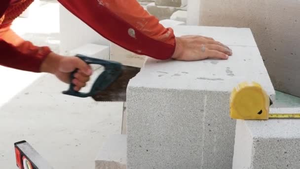 Ein Bauarbeiter Schneidet Mit Der Säge Weiße Ziegelsteine Ein Haus — Stockvideo