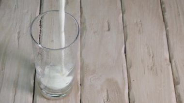 Eski ahşap tahtaların üst manzarasına yoğurt dök. Şeffaf bardaktaki süt içeceği.