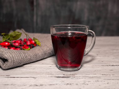 Bir fincan kırmızı gül üzümlü çay, ahşap bir tarzda. Tentür, bitki ya da böğürtlen, kırmızı tıbbi içecek. Homeopati.