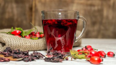 Bir fincanda kırmızı gül üzümü çayı, kırmızı şifalı bitkiler, homeopati. Tahta üzerinde şeffaf bir fincanda nötr çay.