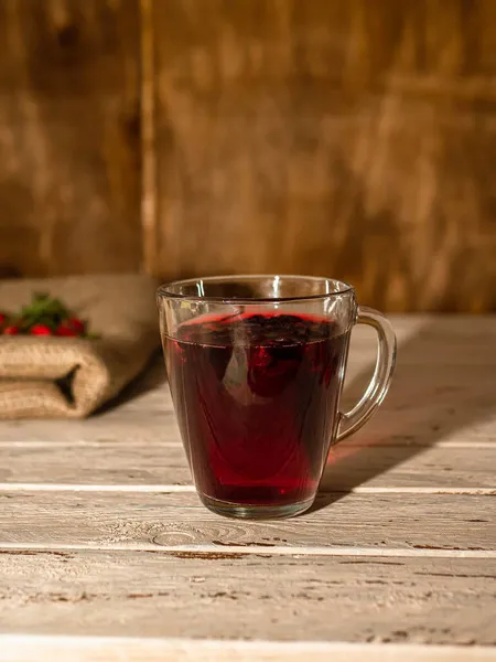 Natural tea in a cup of red rosehip berries in a wooden style. Tincture and herbs or berries, red medicinal drink