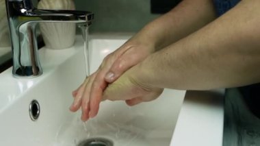 Koronavirüsün önlenmesi ellerinizi sıcak su ve sabunla yıkayın. Hijyen konsepti el detayı, yavaş çekim yaşlı kadın ellerini musluğun altında suyla yıkıyor.