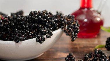 Bir tabakta olgun mürver üzümünün yakın çekimi, böğürtlen şurubu.