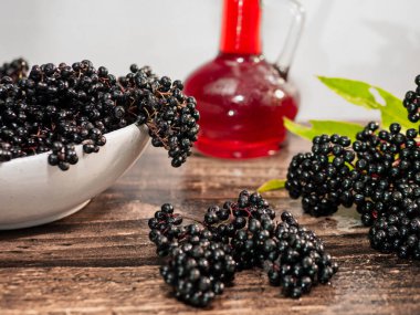 Ahşap bir tahta üzerinde şerbetli olgun mürver. Siyah böğürtlen şifalıdır.