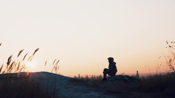 美しい夕日を背景にした若い男の劇的な映像 夕暮れ時の山の上の男 — ストック動画