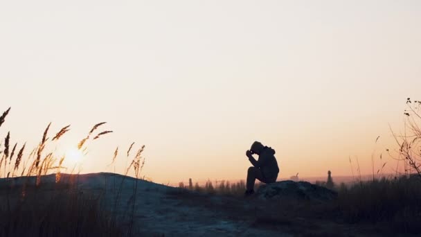 美しい夕日を背景に若い男 日没時に山の上の男 悲しみやうつ病の男 — ストック動画